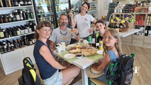 Eine Familie mit Kindern und eine Mitarbeiterin im Verkostungsraum in Salerno, mit Oliven, Brot, Wurstwaren und Käse auf dem Tisch