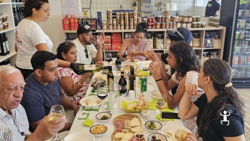 Teilnehmende sitzen an einer langen Tafel mit Oliven, Wurstwaren, Käse und Brot, während eine Mitarbeiterin in Salerno, Kampanien, Olivenöl ausschenkt