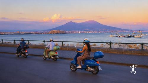 Tour panoramico in Vespa tra le strade di Napoli illuminate dal tramonto, ideale per coppie e piccoli gruppi