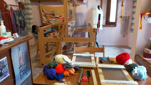 Interno della bottega di tessitura a Bisaccia, con un grande telaio in legno, sciarpe esposte e telai a cornice sul tavolo.