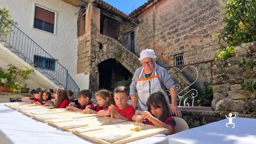 Bambini lavorano l’impasto su spianatoie in legno, affiancati da una cuoca locale nel cortile del laboratorio a Castel Morrone.