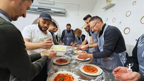 Partecipanti con grembiule ascoltano il pizzaiolo nel laboratorio di pizza a Napoli