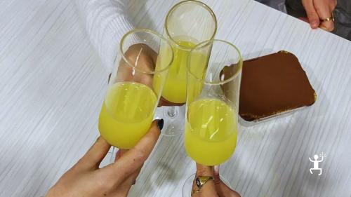 Partecipanti brindano con bicchieri di liquore giallo accanto a una porzione di tiramisù