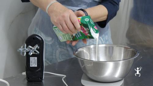 Una partecipante versa il latte in una ciotola di acciaio durante il laboratorio di gelato a Napoli.