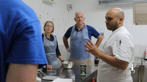 Lo chef spiega la preparazione del gelato ai partecipanti riuniti intorno al banco del laboratorio a Napoli.