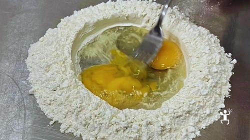Eier und Mehl auf der Arbeitsfläche bei der Teigzubereitung während eines Kurses für frische Pasta in Neapel.