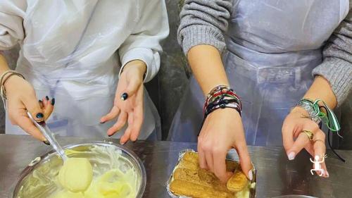 Teilnehmende schichten Löffelbiskuits und Creme zu einem Tiramisu während des Kochkurses in der Altstadt von Neapel.