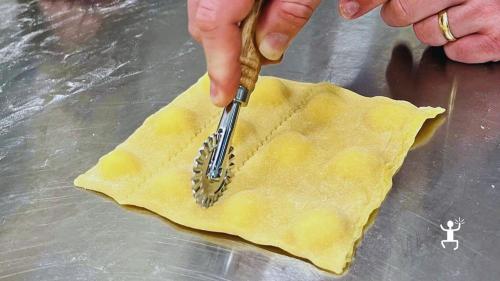 Schneiden der Ravioli mit einem gezackten Teigrädchen während des Pastakurses in der Altstadt von Neapel.