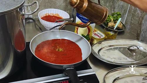 Zubereitung der Tomatensauce in einer Pfanne für die frische Pasta während des Kochkurses in Neapel.