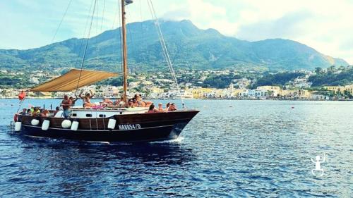 Barca con vista panoramica tra le acque cristalline di Ischia in Campania durante un'esperienza per famiglie con pranzo a bordo 